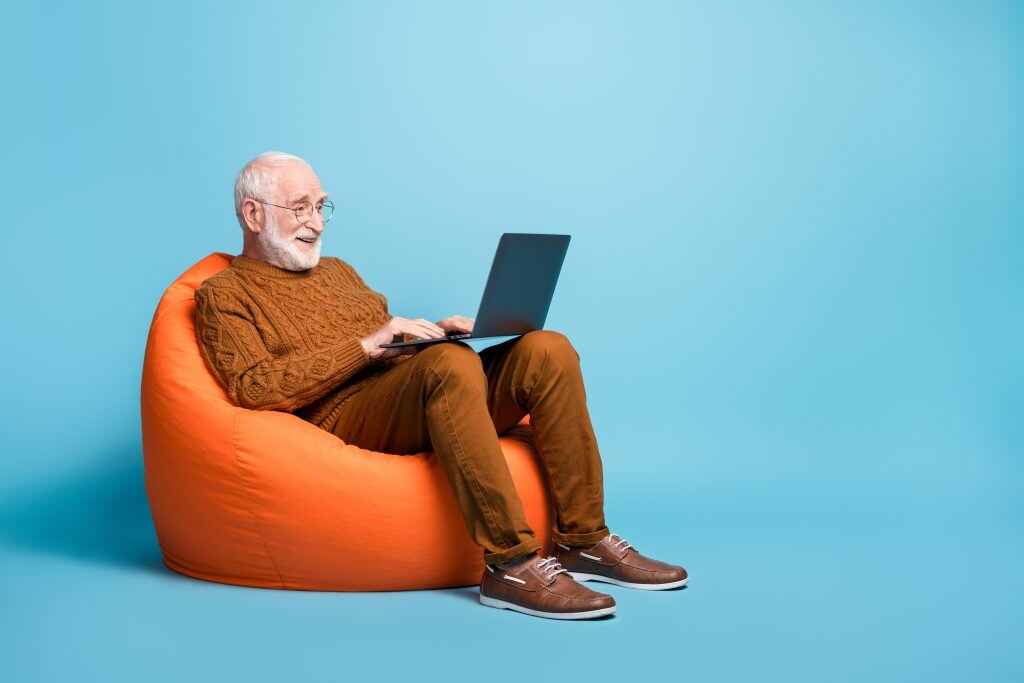 portrait-of-his-he-nice-attractive-focused-bearded-grey-haired-man-sitting-in-bag-chair-using-laptop-writing-email-letter-browsing-web-wi-fi-isolated-over-blue-pastel-color-background-stockpack-istock-1024x683